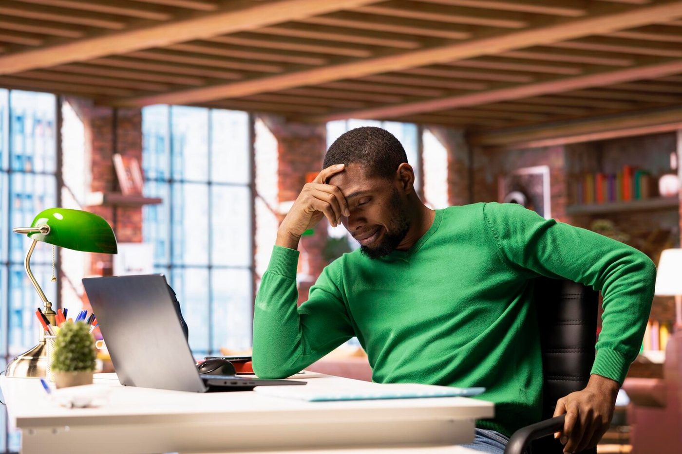 Exhausted man resting his head in his hand at his desk