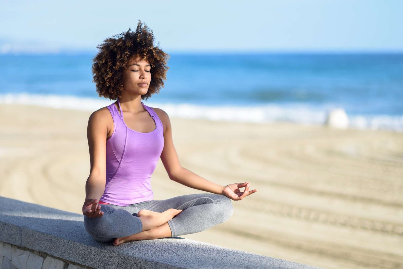 Woman sitting cross-legged and meditating calmly outdoors